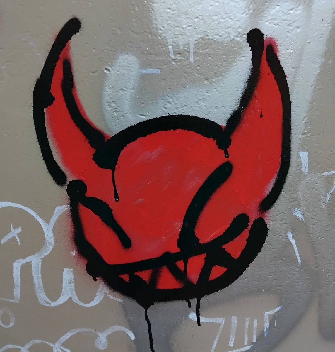 Pulse red devil graffiti tag sprayed on a wall